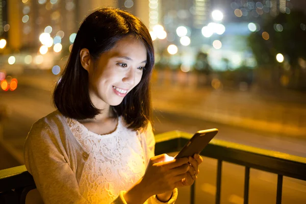 Geceleri cep telefonu kullanan bir kadın.