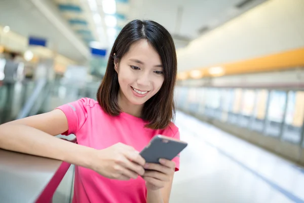 Vrouw met behulp van mobiele telefoon op perron — Stockfoto