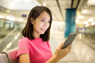 Tren platformu cep telefonu kullanan kadın