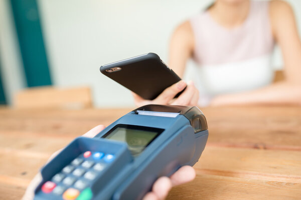 Woman using cellphone for paying the bill