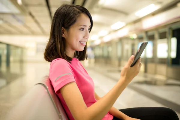 Vrouw met behulp van mobiele telefoon op station — Stockfoto