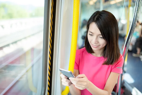 Kvinna med hjälp av mobiltelefon inne i tåget — Stockfoto