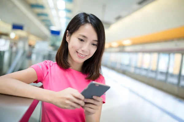 Vrouw met behulp van mobiele telefoon op station — Stockfoto