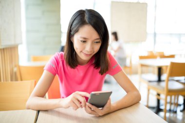 Café'de cep telefonu kullanan kadın