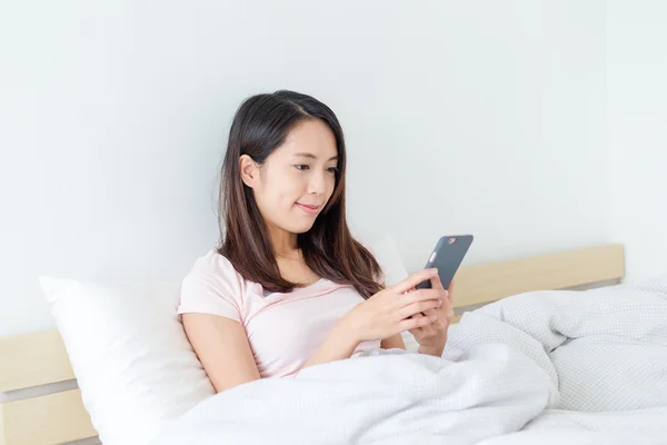 Woman using cellphone on bed — Stock Photo, Image