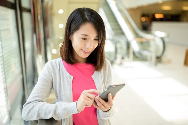 Vrouw met mobiele telefoon in het winkelcentrum — Stockfoto