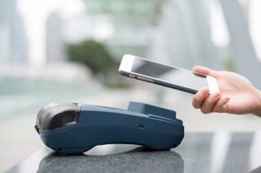 Fatura ödeme için cep telefonu kullanan kadın