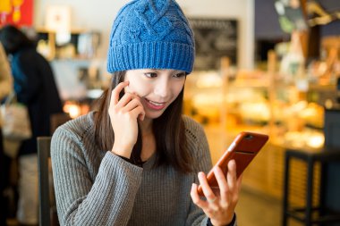 Kahve dükkanında cep telefonu kullanan kadın