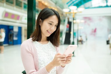 alışveriş merkezinde cep telefonu kullanan kadın