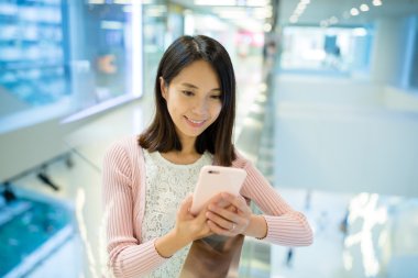 alışveriş merkezinde cep telefonu kullanan kadın