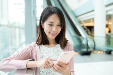 alışveriş merkezinde cep telefonu kullanan kadın