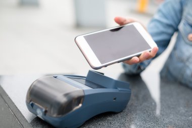 Fatura ödeme için cep telefonu kullanan kadın