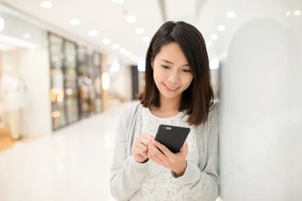 Vrouw met behulp van de mobiele telefoon bij winkelcentrum — Stockfoto