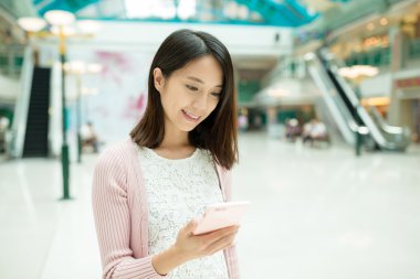 alışveriş merkezinde cep telefonu kullanan kadın