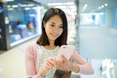 alışveriş merkezinde cep telefonu kullanan kadın