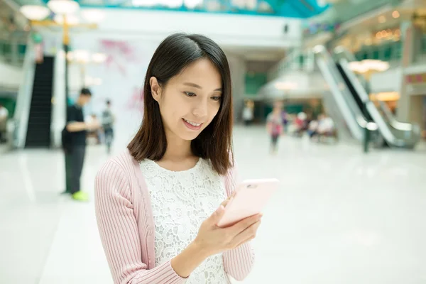 Vrouw met behulp van smart phone in het winkelcentrum — Stockfoto