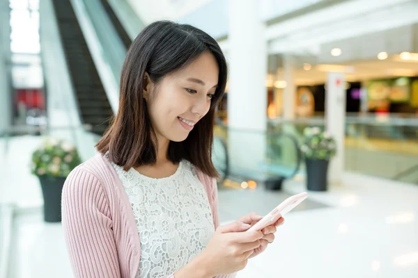 Alışveriş merkezinde akıllı telefon kullanan bir kadın.