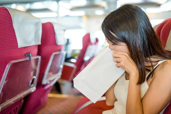 Woman feeling unwell and vomit in paper bag — Stock Photo, Image