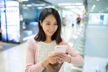 Alışveriş merkezinde cep telefonu kullanan kadın