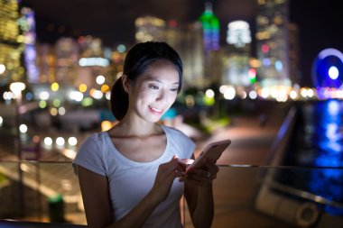 Geceleri cep telefonu kullanan bir kadın.