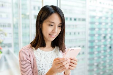 Alışveriş merkezinde akıllı telefon kullanan bir kadın.