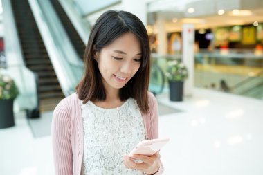 alışveriş merkezinde cep telefonu kullanan kadın