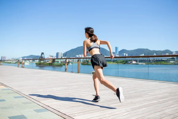 Sportiga kvinnan körs på strandpromenaden — Stockfoto