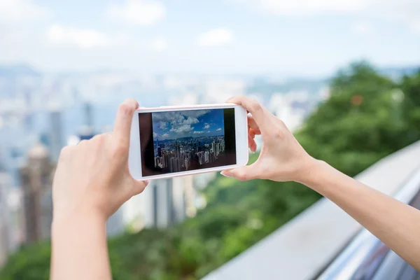 Vrouw met behulp van mobiele telefoon te nemen van de foto van Hong Kong city — Stockfoto