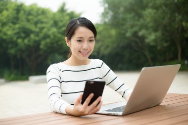 cep telefonu ve dizüstü bilgisayar kullanan kadın