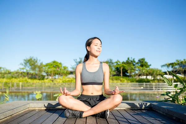 Kvinde sidder i yoga positur i parken - Stock-foto