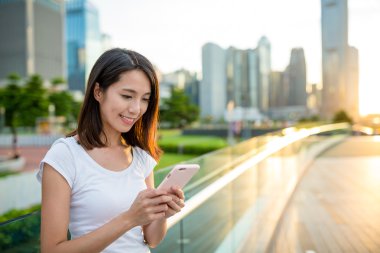 gün batımında kadın usingn cep telefonu