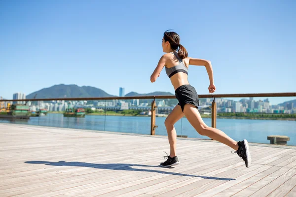 Woman running on seaside boardwalk — Stock Photo, Image