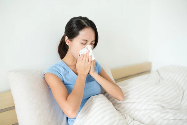 Asian woman sneezing on bed — Stock Photo, Image