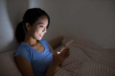 cep telefonu kullaranarak ve yatağın üstüne oturan kadın