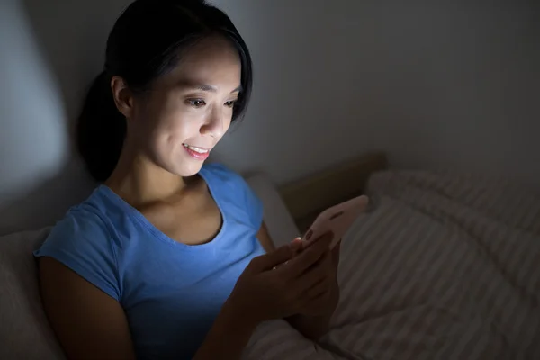 Mujer usando el teléfono móvil y sentado en la cama —  Fotos de Stock