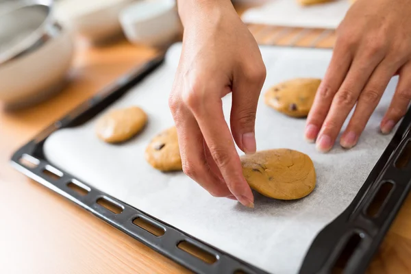 Kvinnan sätter cookies på metall bricka — Stockfoto