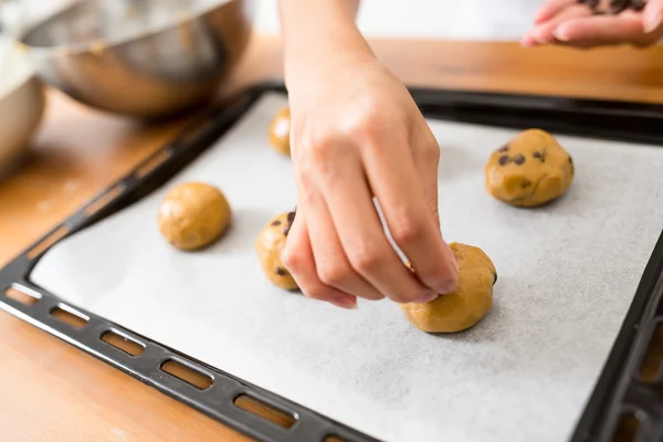 Woman putting cookies on metal tray — Stock Photo, Image