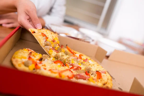 Vrouw nemen uit een plak van pizza — Stockfoto