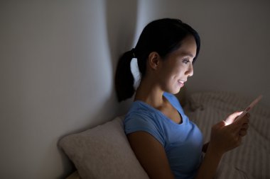 Geceleri cep telefonu kullanan bir kadın.