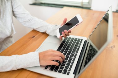 cep telefonu ve dizüstü bilgisayar kullanan kadın