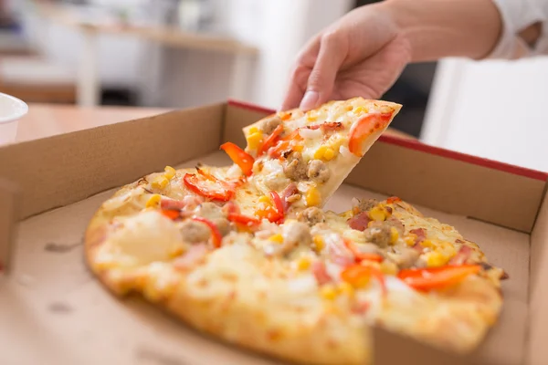 Vrouw nemen uit een plak van pizza — Stockfoto