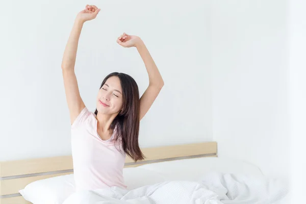 Kvinnan sträcker händerna i sängen — Stockfoto