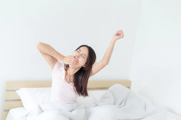 Woman yawning on bed at home — Stock Photo, Image