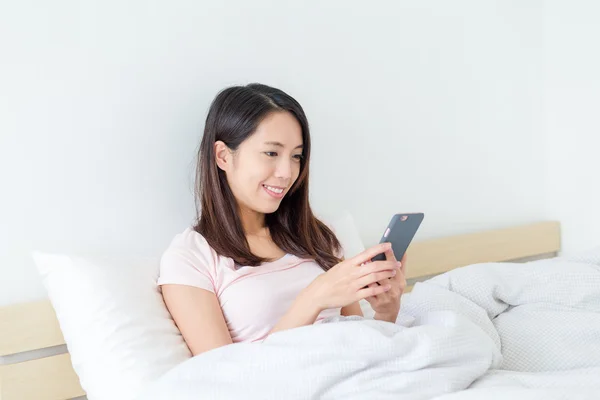Wanita menggunakan ponsel di tempat tidur — Stok Foto
