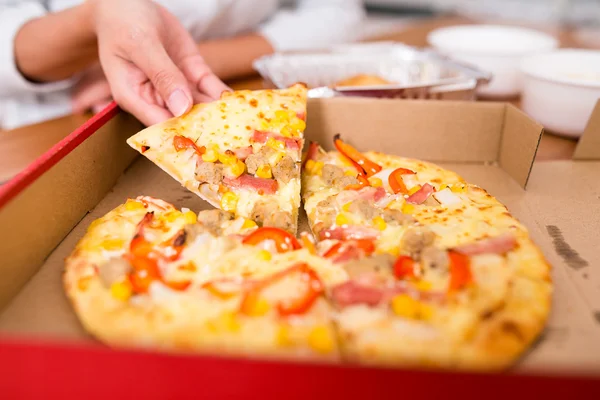 Vrouw nemen uit een plak van pizza — Stockfoto