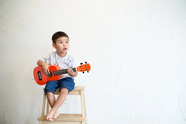 Kleiner Junge spielt mit Ukulele — Stockfoto