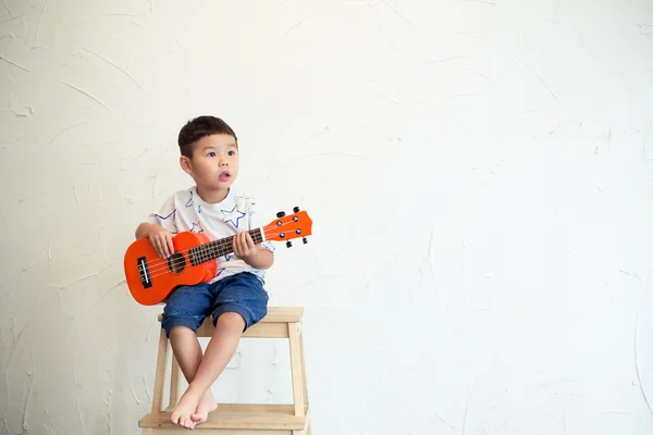 Мальчик играет с укулеле — стоковое фото
