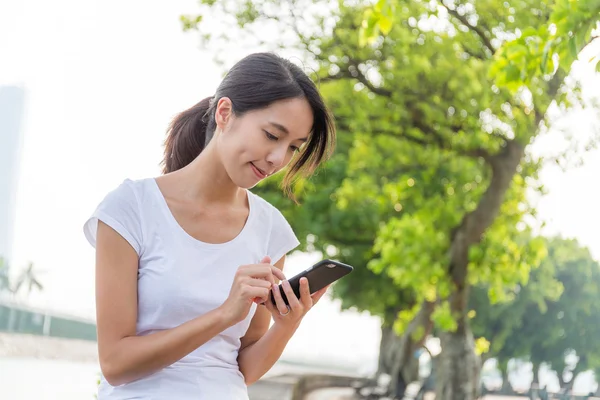 Vrouw met mobiele telefoon in het park — Stockfoto