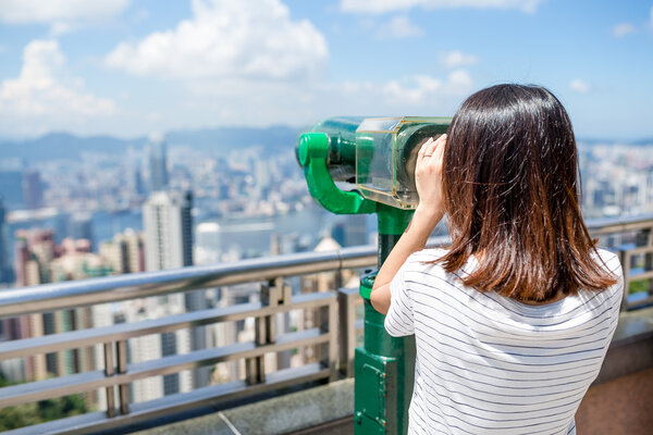 Woman looking though the binocular in the Peak of Hong Kong