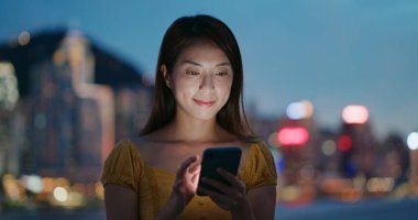 Kadın akşam vakti cep telefonu kullanıyor.